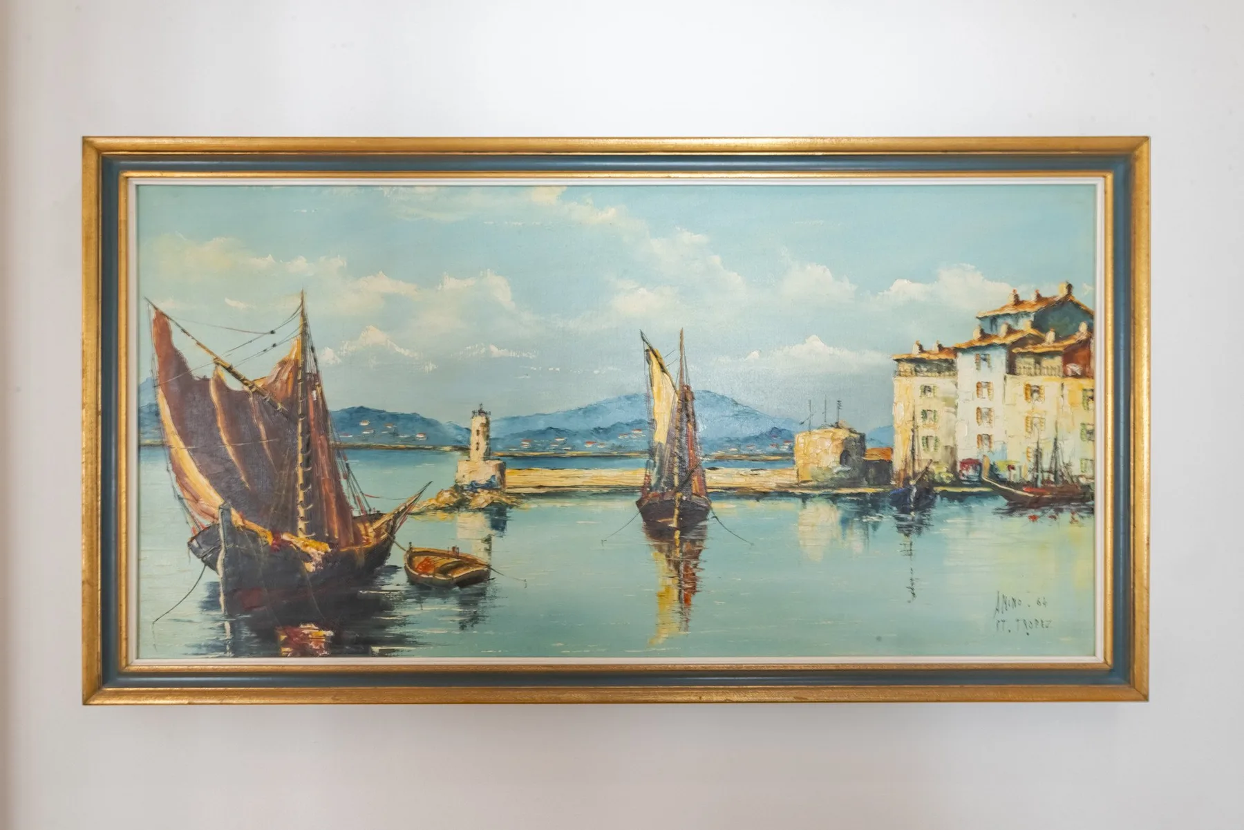 A framed harbor painting hangs on a plain wall.