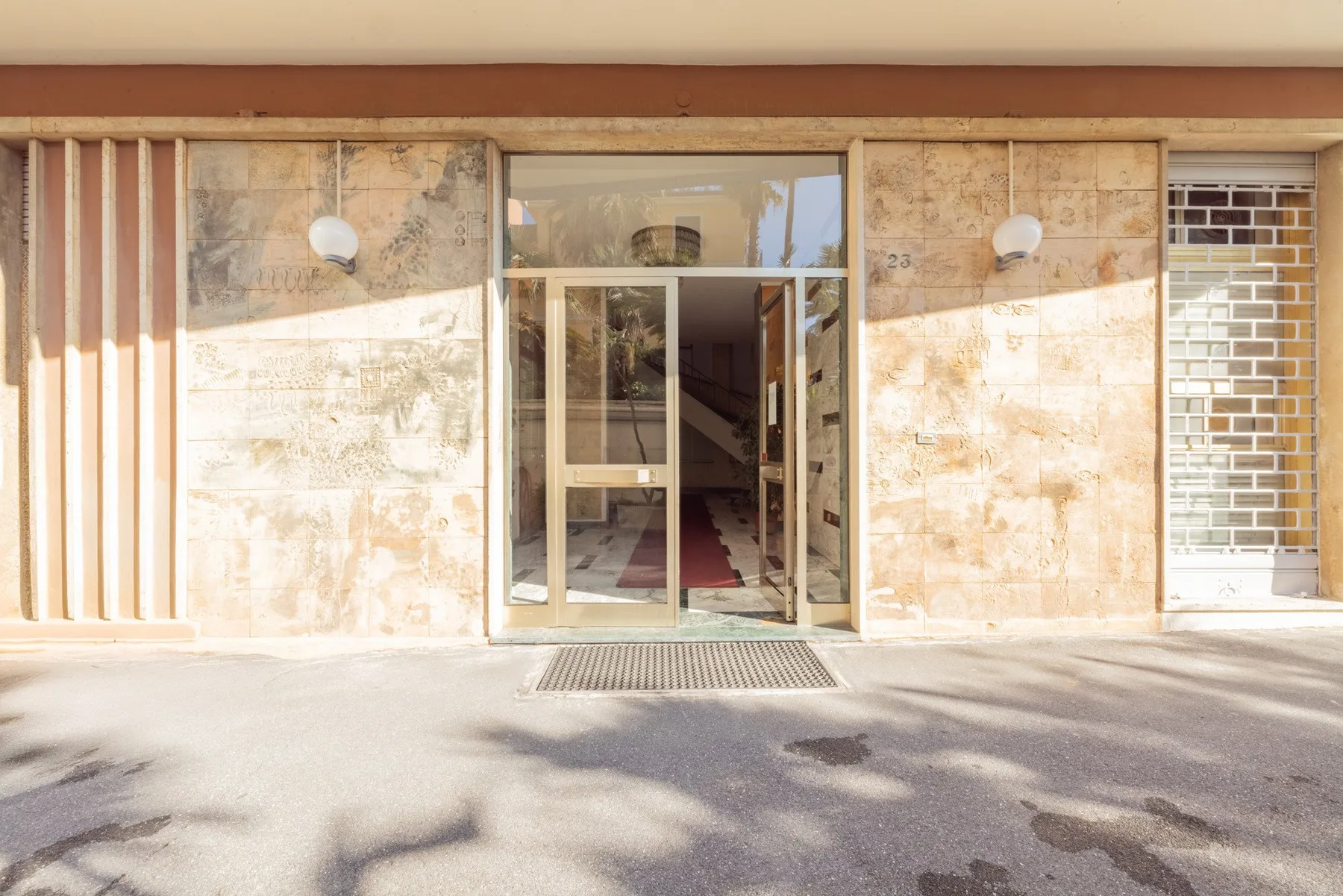 A building entrance with glass doors set into a stone facade.