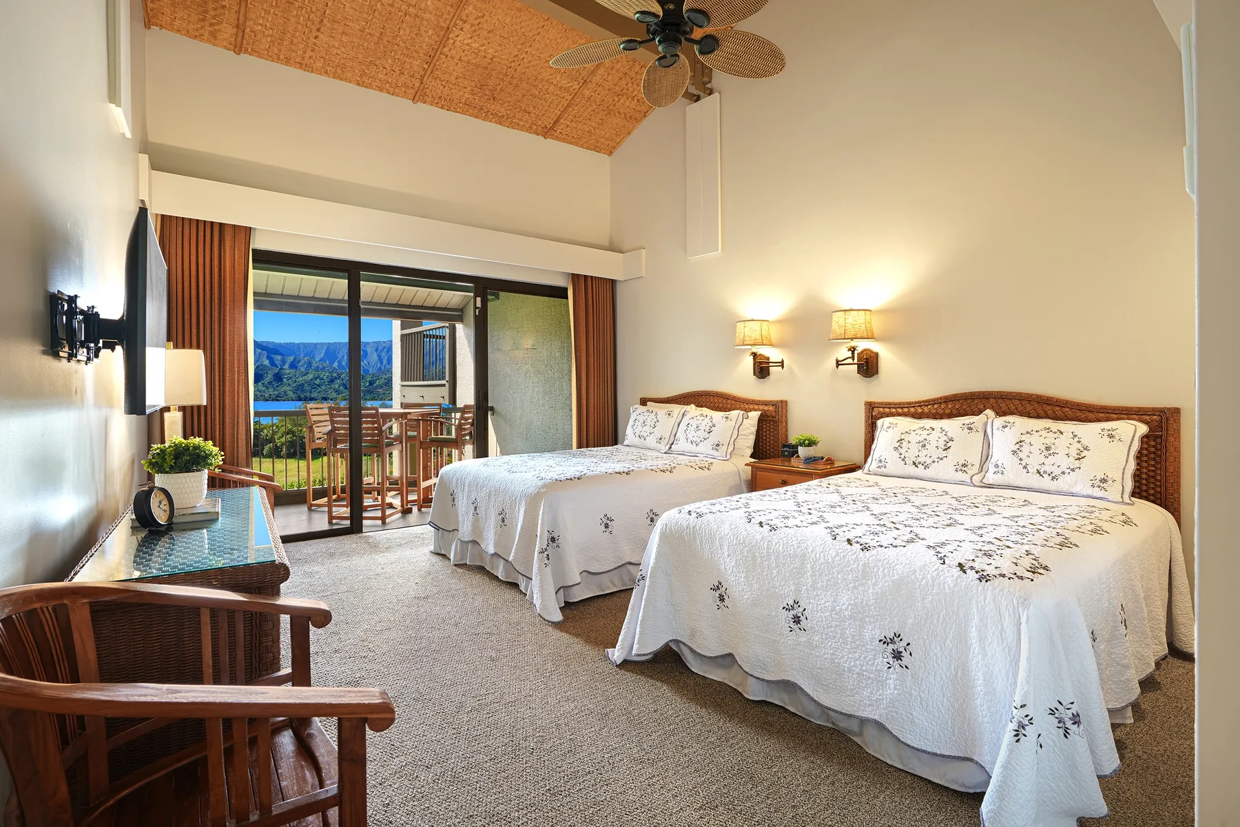 A bedroom with two beds and glass doors opening onto a balcony.