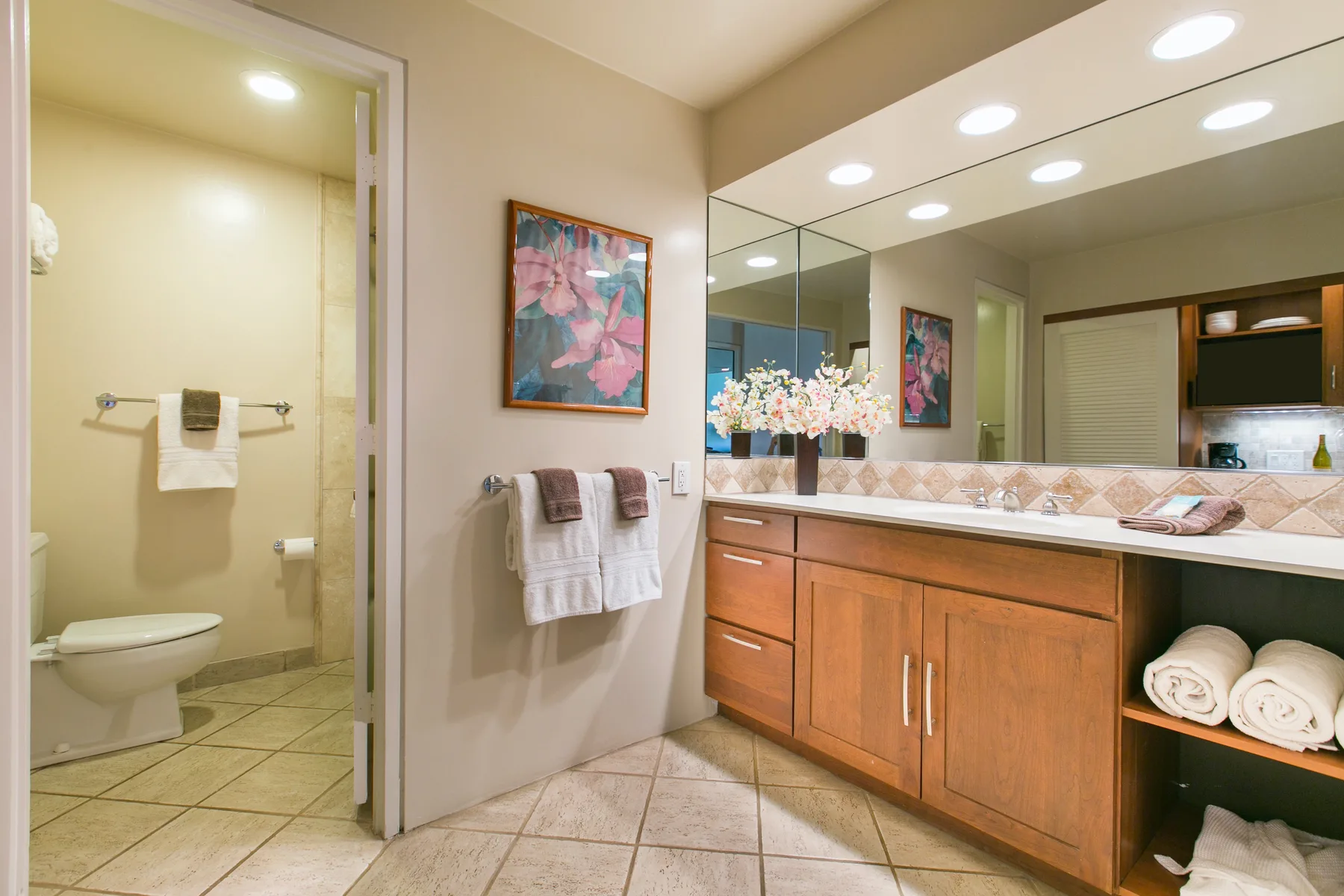 A bathroom with a long wooden vanity, broad mirror, and towels.