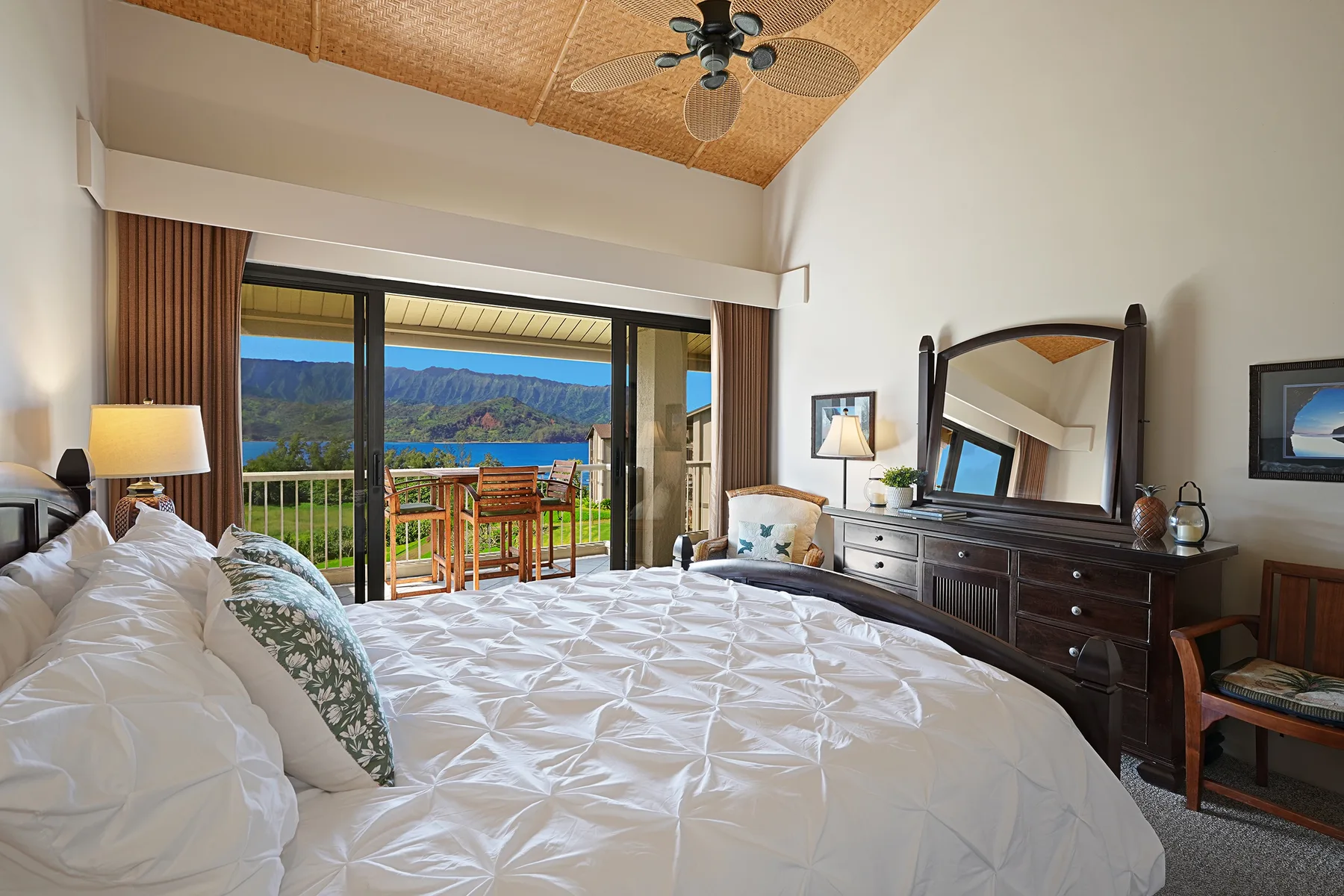 A bedroom with a bed beside open glass doors leading to a balcony.