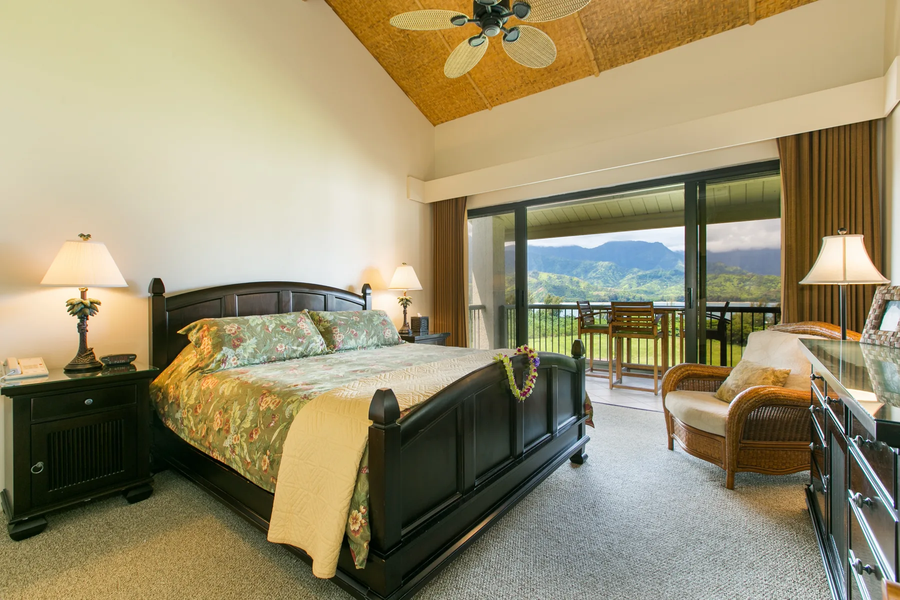 A bedroom with a large bed, bedside lamps, and sliding glass doors overlooking mountains.