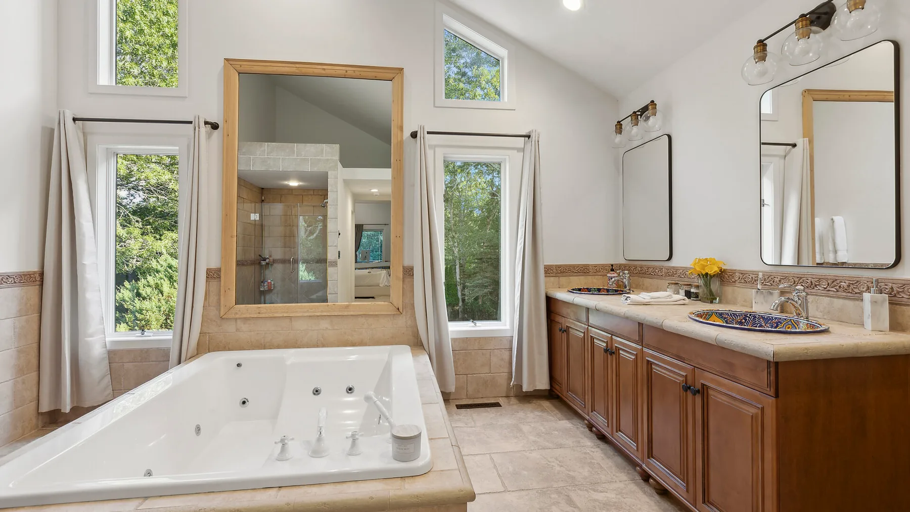 Un baño luminoso con una bañera grande y un mueble de lavabo largo.