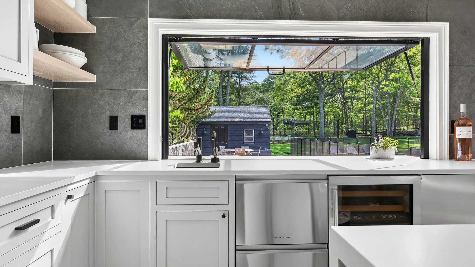 Una cocina moderna con una amplia ventana que da a un patio arbolado.