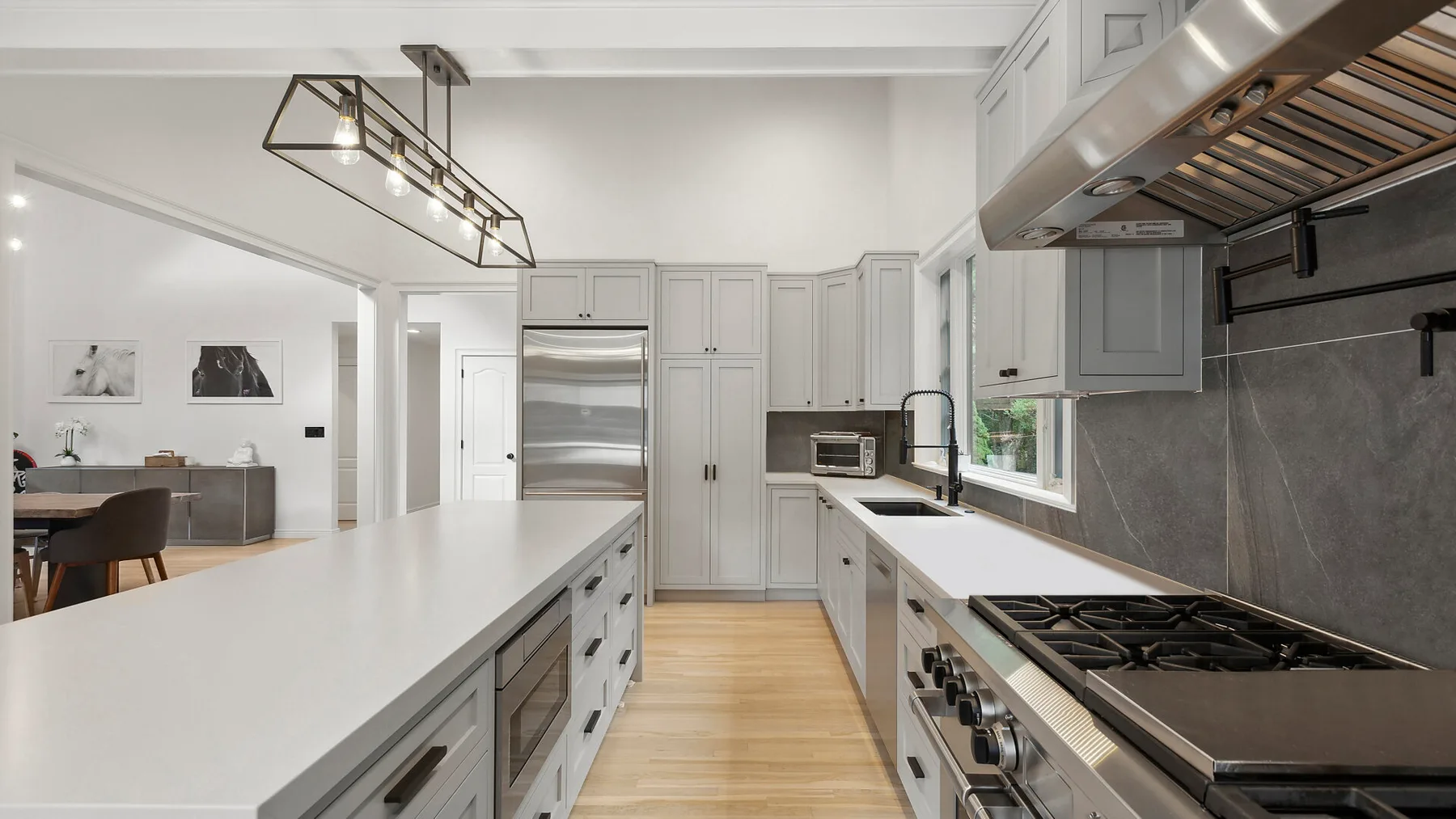 Una cocina luminosa con gabinetes blancos, encimeras largas y una isla central.