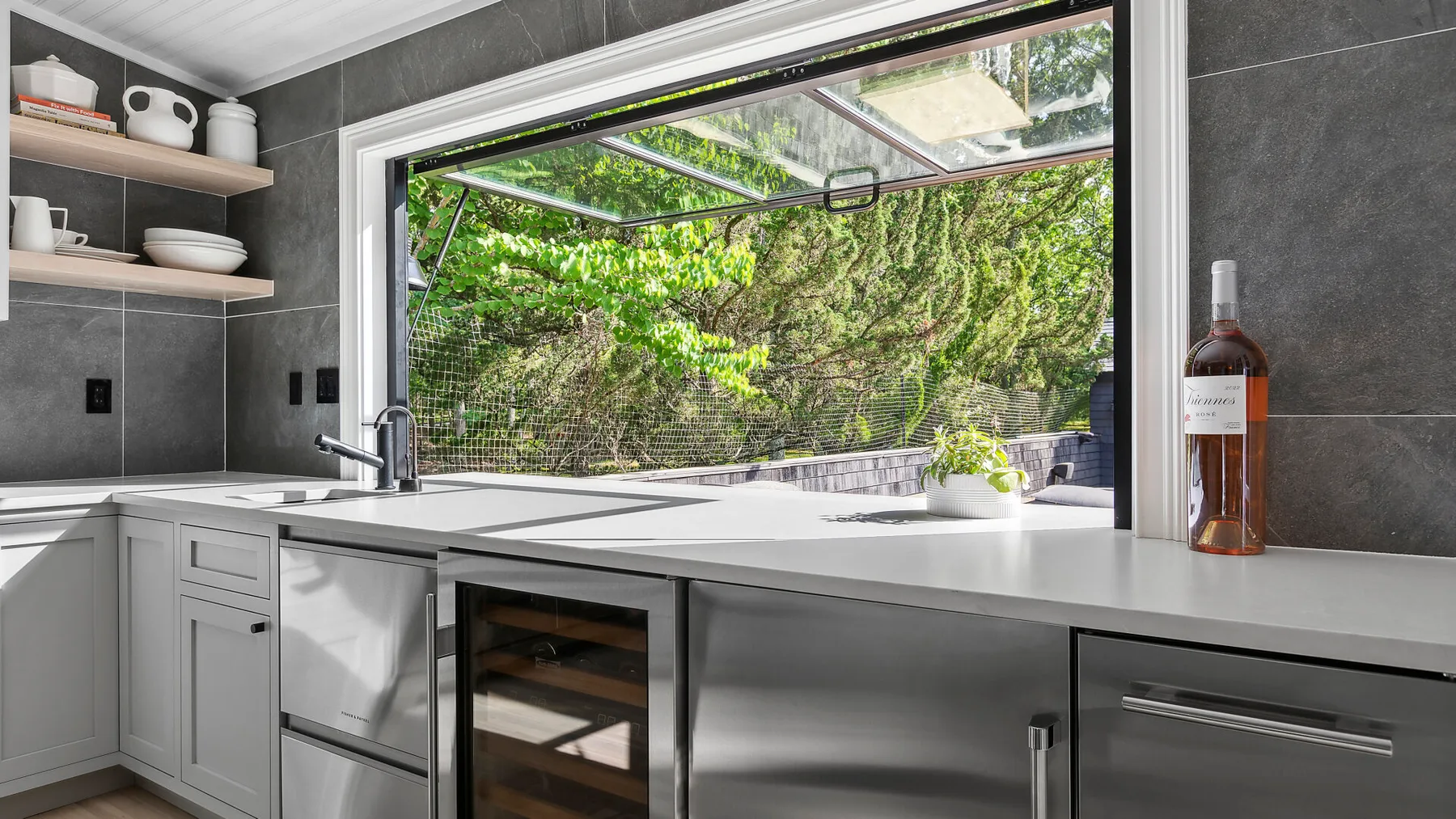 Una cocina moderna con una encimera amplia y una ventana que da a la vegetación.
