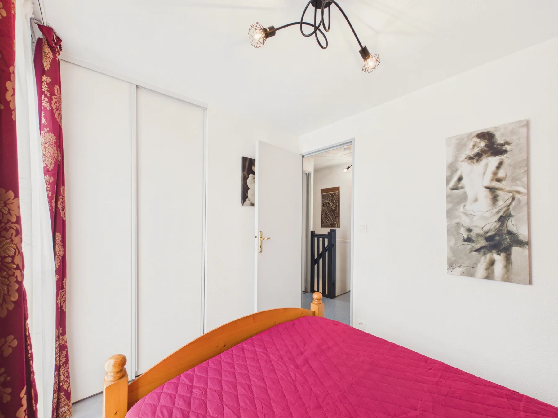 A bedroom with a bed covered by a bright pink quilt.