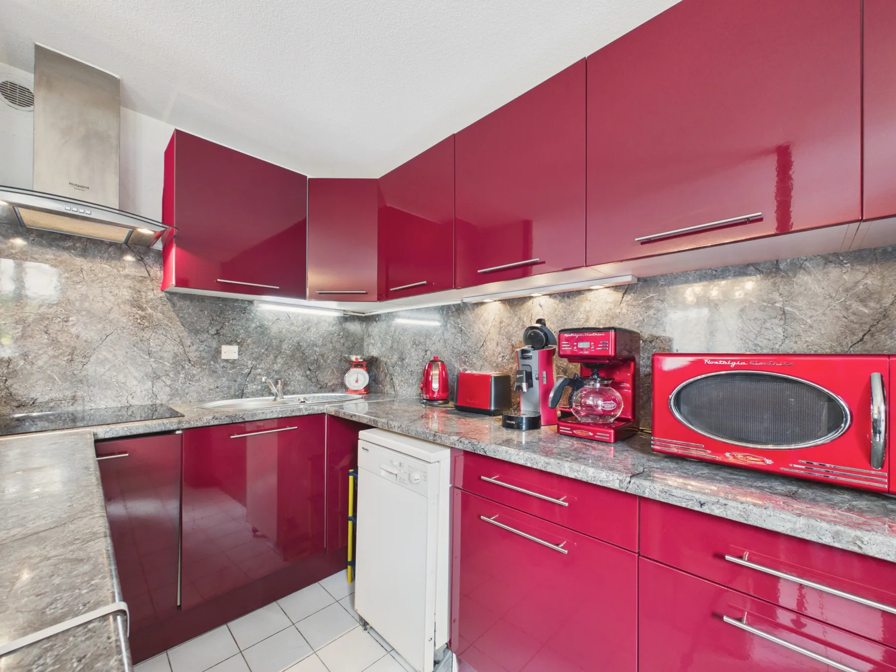 A kitchen with red cabinets, gray countertops, and small appliances.