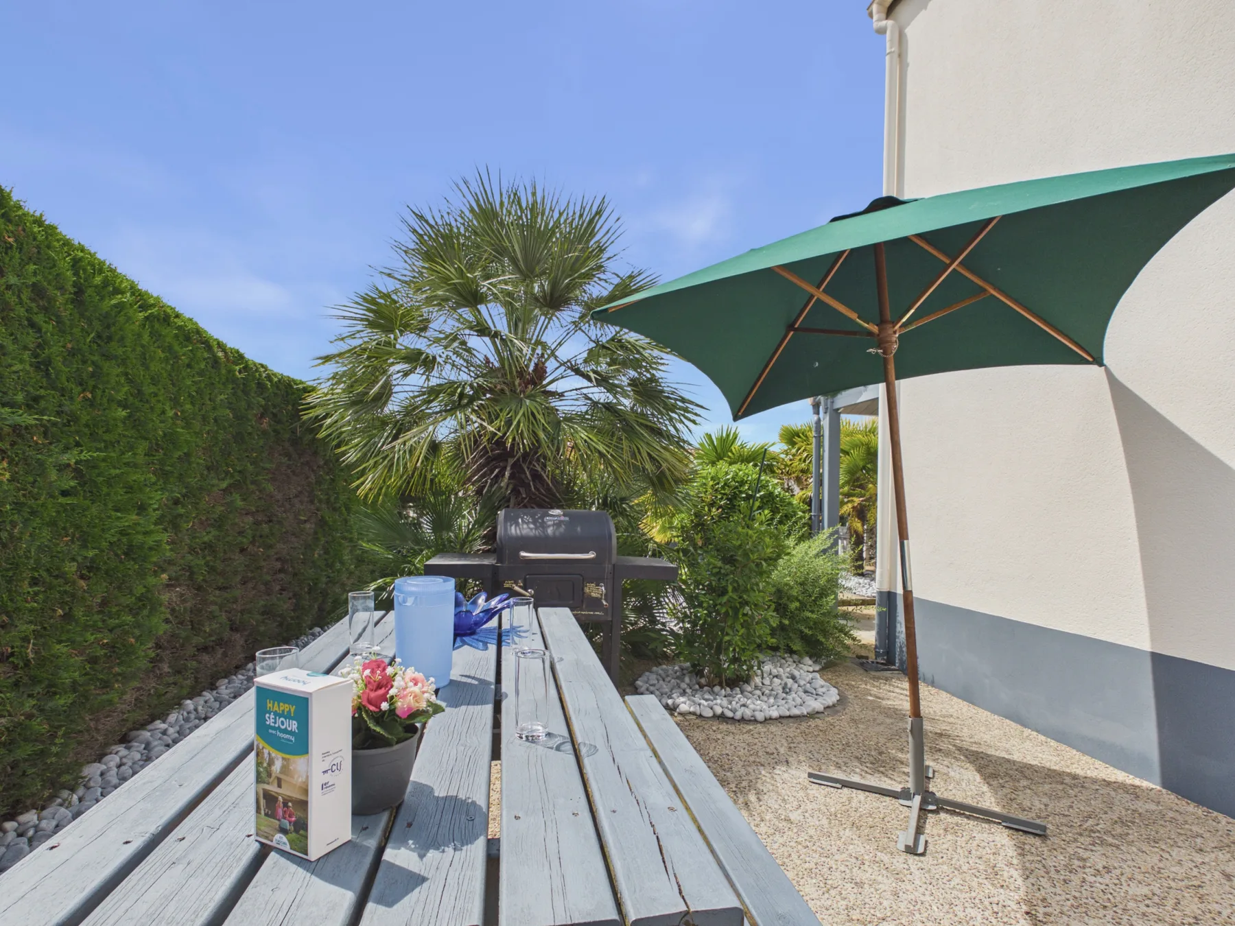 Outdoor patio with a picnic table, umbrella, and garden plants.