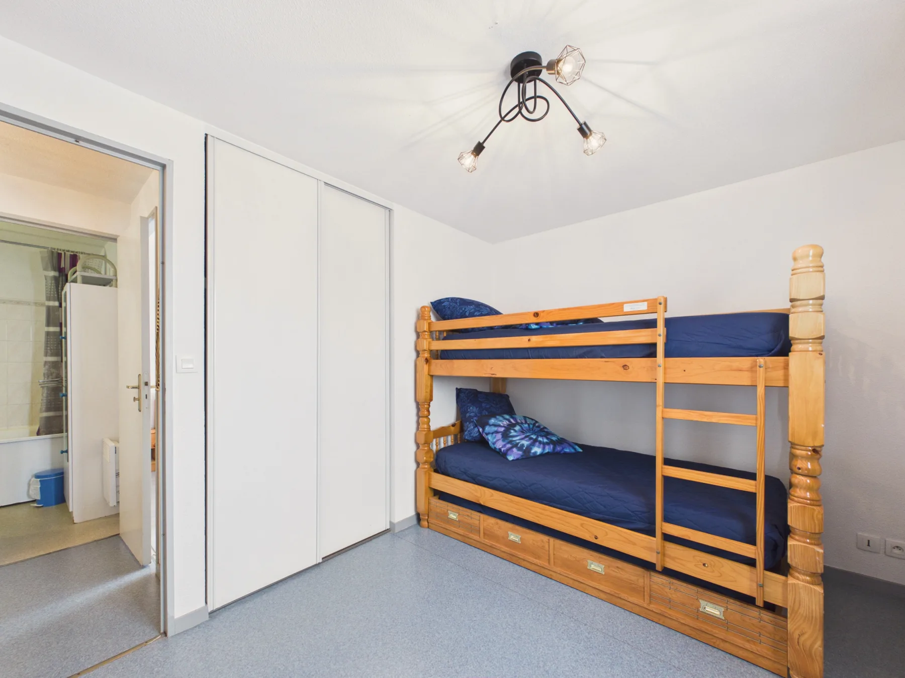 A bedroom with wooden bunk beds and built-in storage.