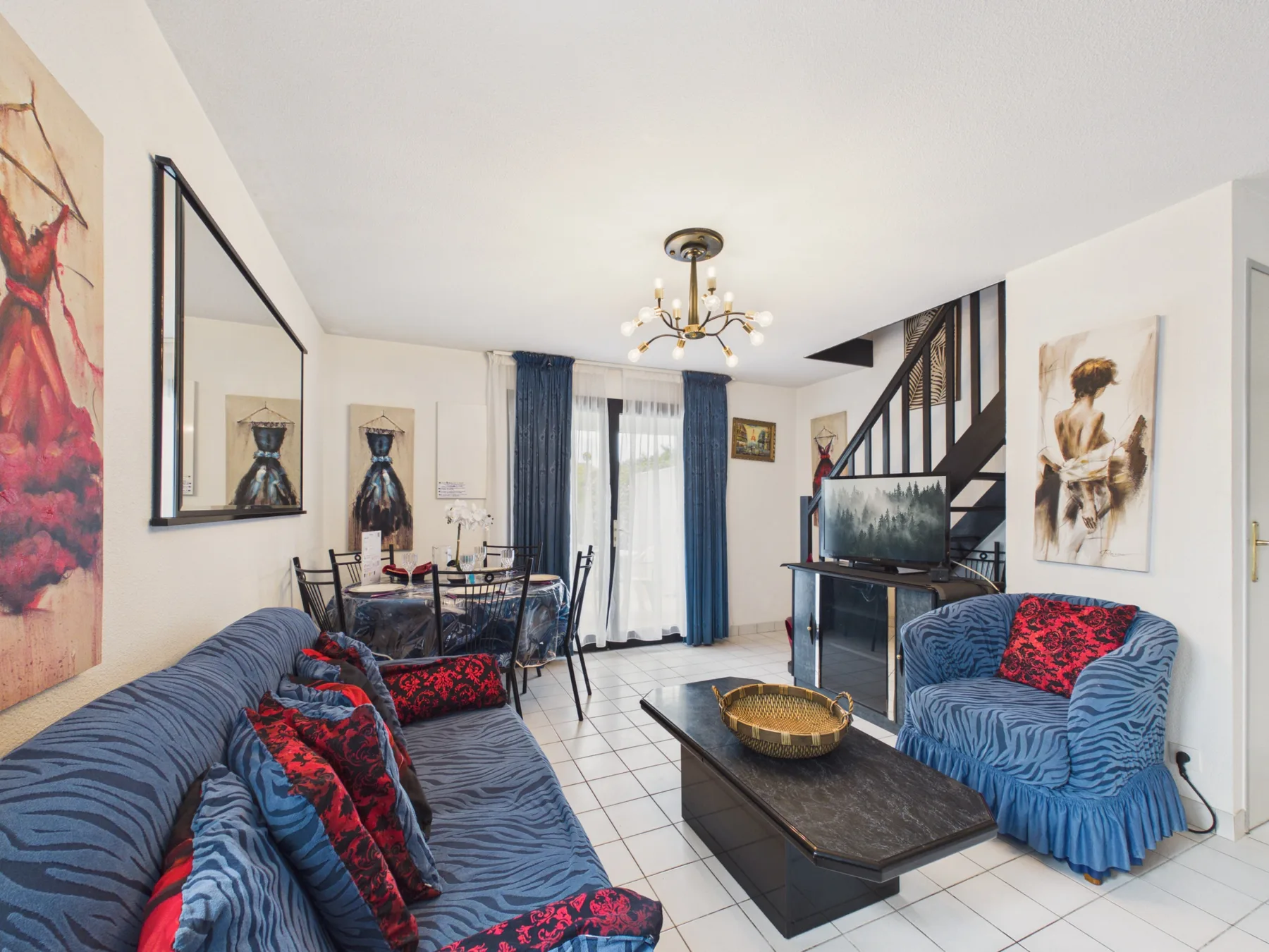 Living room with blue seating, a coffee table, and a staircase.