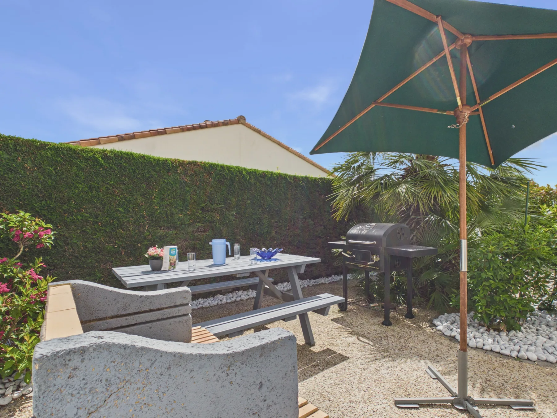Outdoor patio dining area with picnic table, seating, and a barbecue.