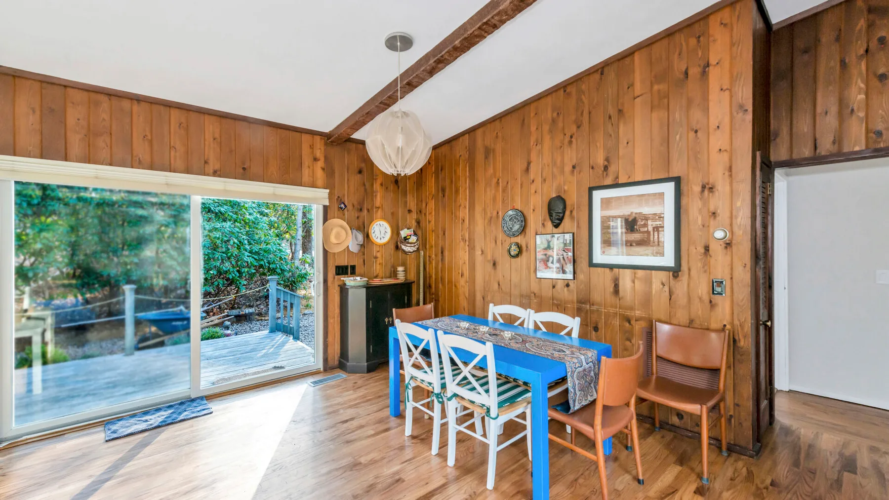 Un comedor revestido de madera con una mesa azul junto a puertas corredizas de vidrio.