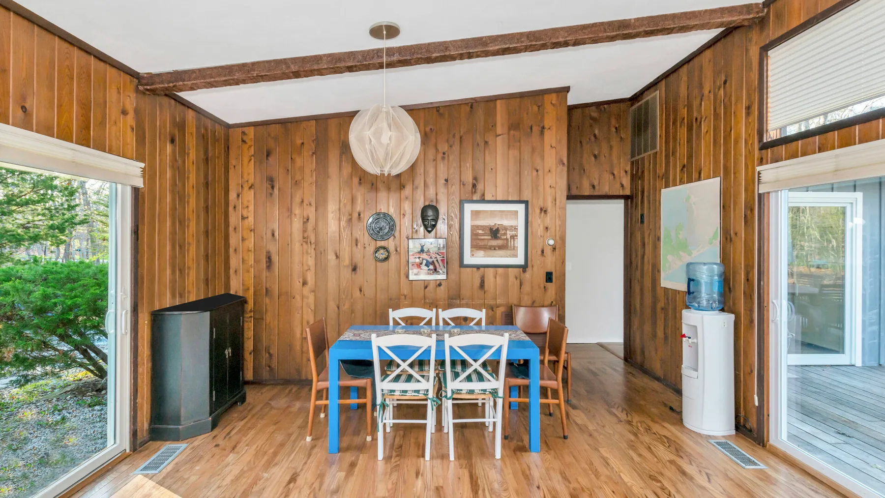 Comedor revestido de madera con una mesa azul y sillas.