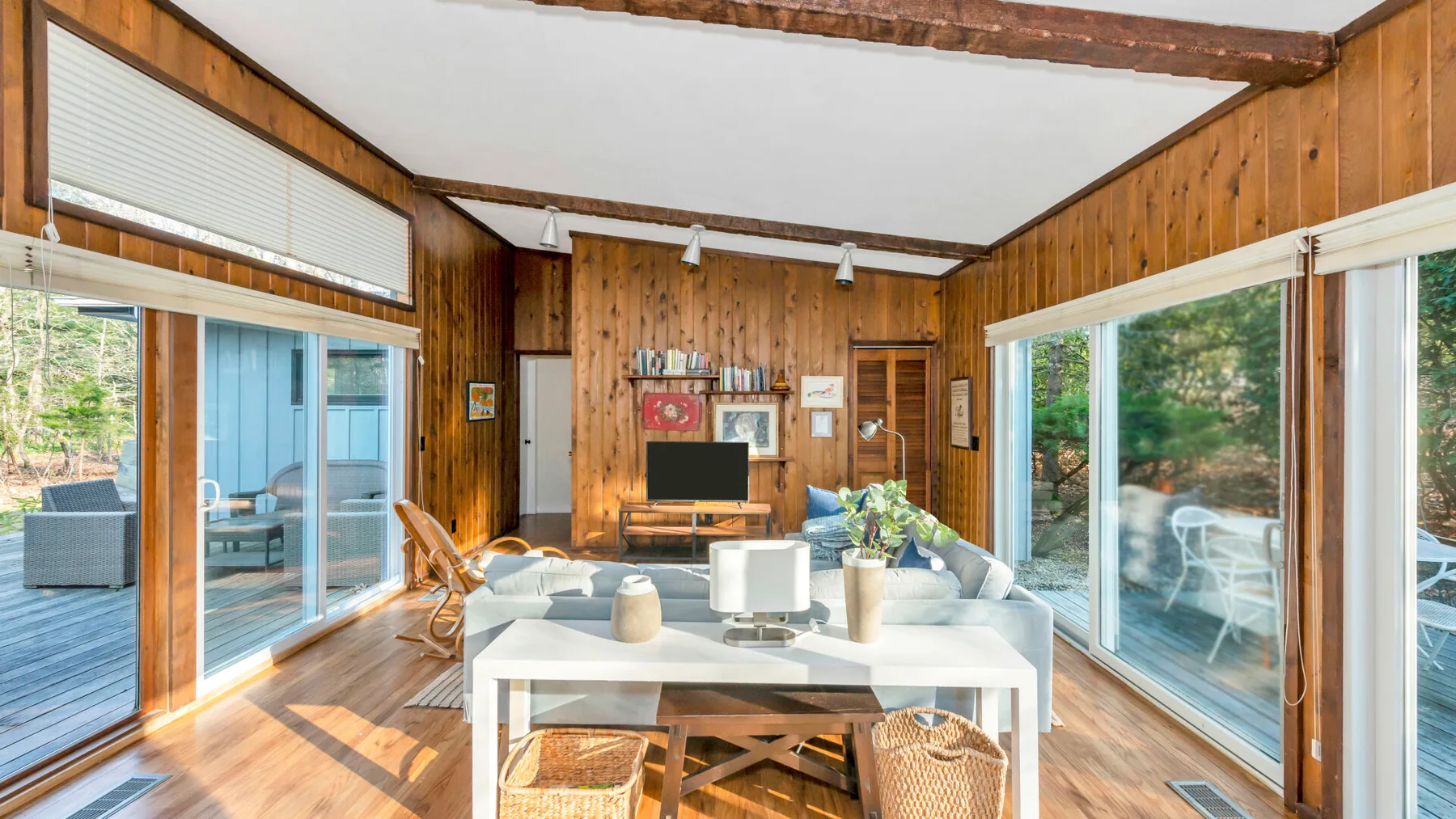 Una sala de estar y comedor con paneles de madera, asientos y ventanales.