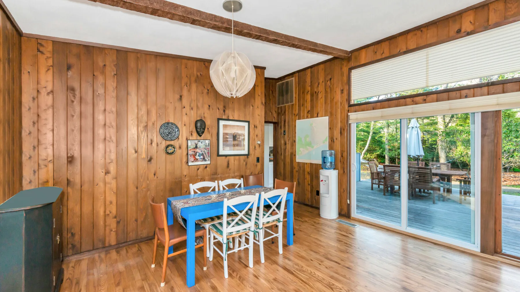 Un comedor revestido de madera con una mesa junto a amplias puertas corredizas de vidrio.