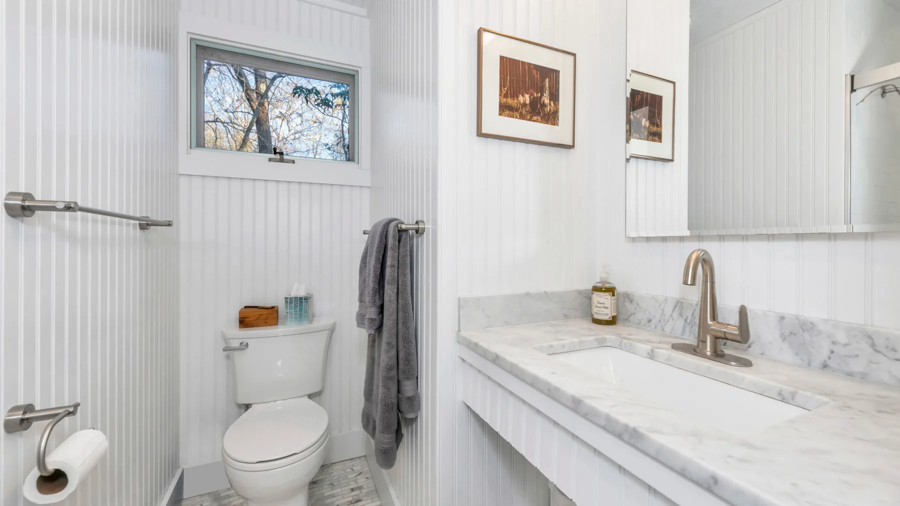Un baño luminoso con inodoro, toallas y un largo lavabo con superficie jaspeada.