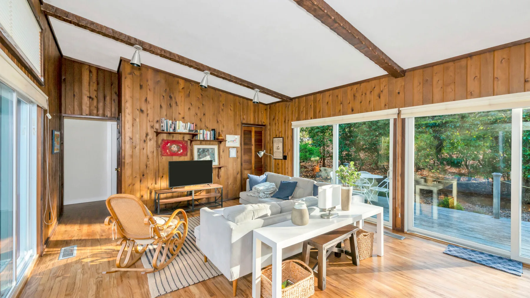 A wood-paneled living room with seating, a television, and large glass doors.