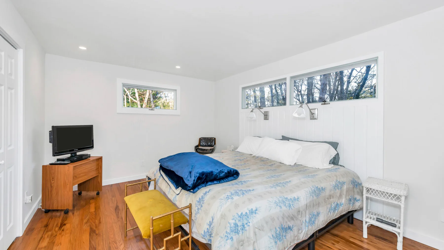 Un dormitorio con una cama grande, un televisor y una silla pequeña.