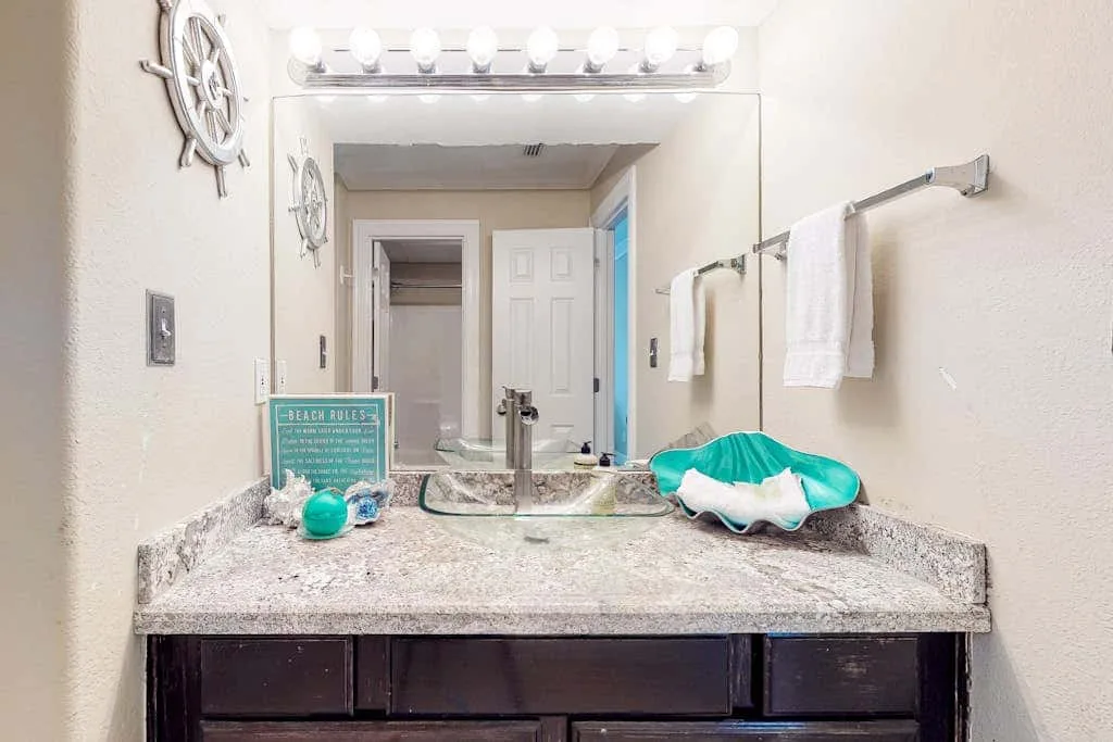 Un lavabo de baño con un espejo amplio y toallas colgadas al lado.