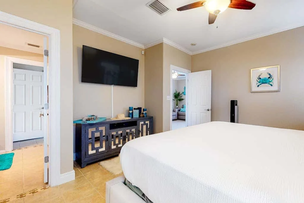 Un dormitorio con una cama grande, un televisor en la pared y un mueble.