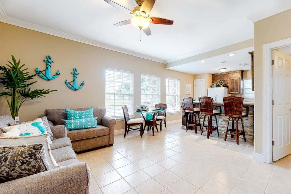 A living and dining area with seating, a table, and a kitchen counter.