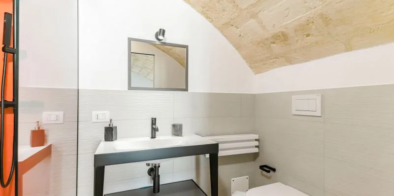 A bathroom with a wide sink, wall mirror, and sloped ceiling.