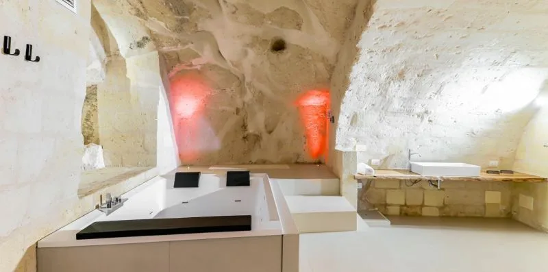 A stone bathroom features a bathtub beneath an arched ceiling.