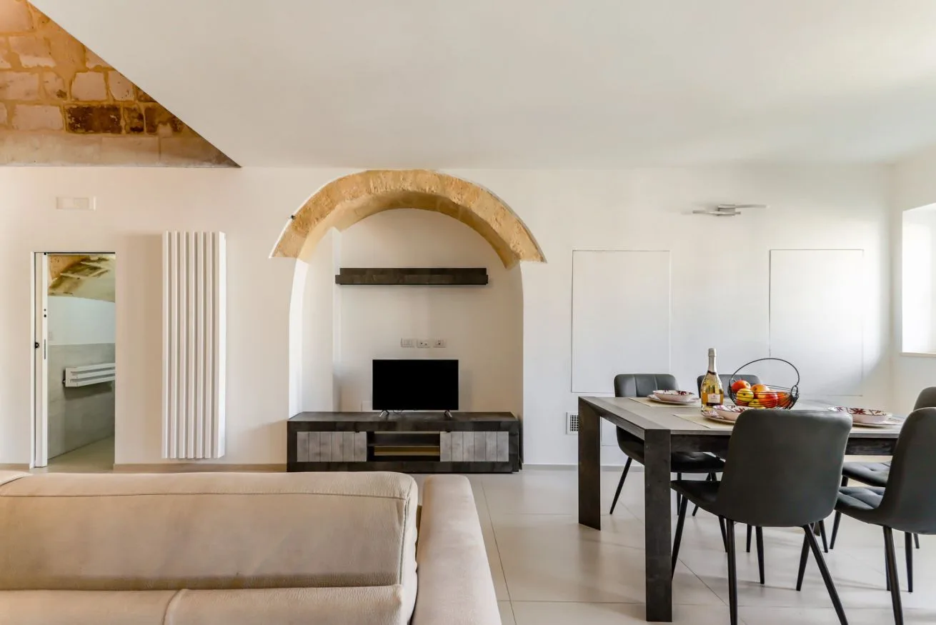Living and dining area with a television beneath an arched stone feature.