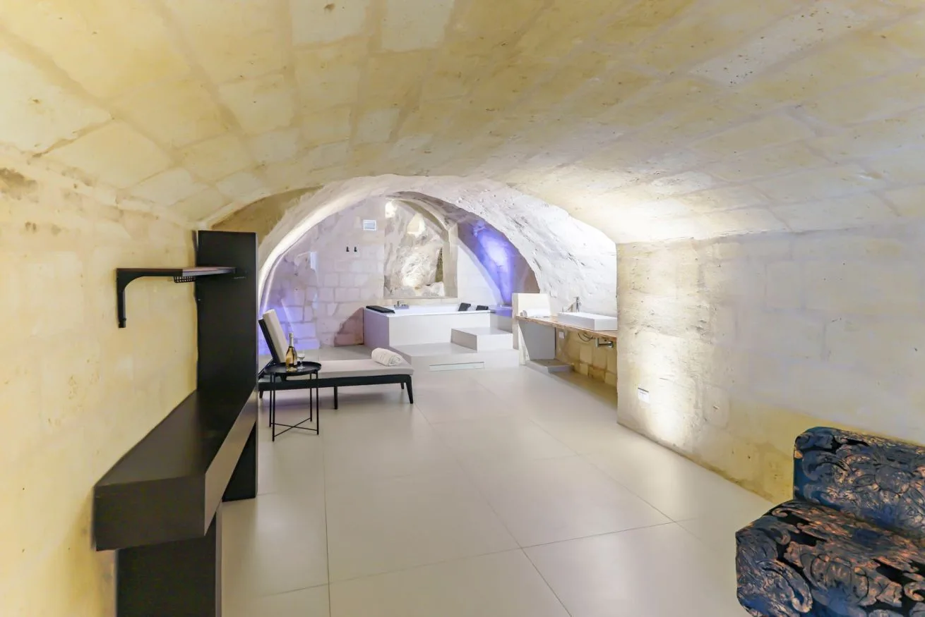 A stone interior room with arched ceilings and a small seating area.