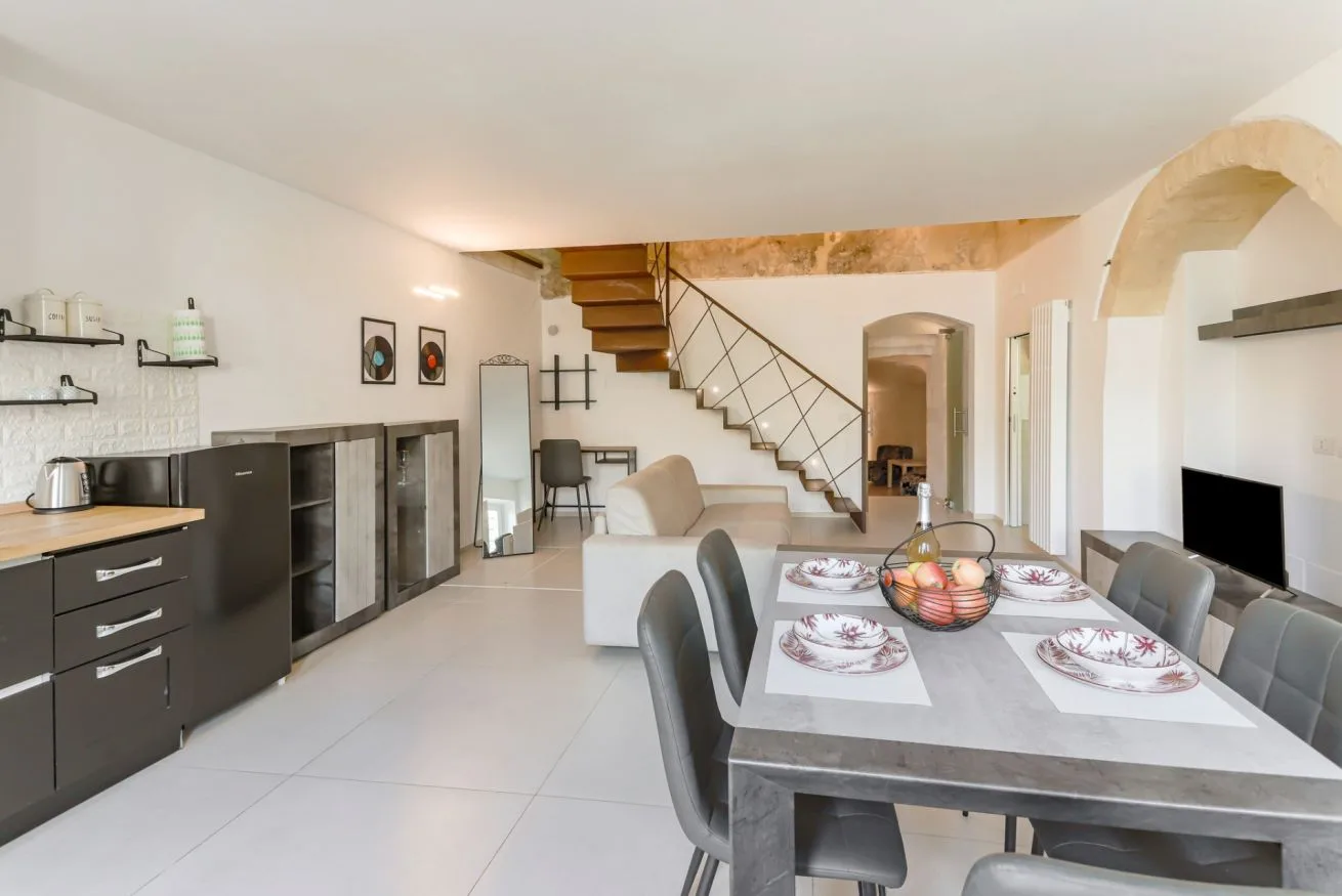 An open-plan dining and living area with a table, seating, and a staircase.