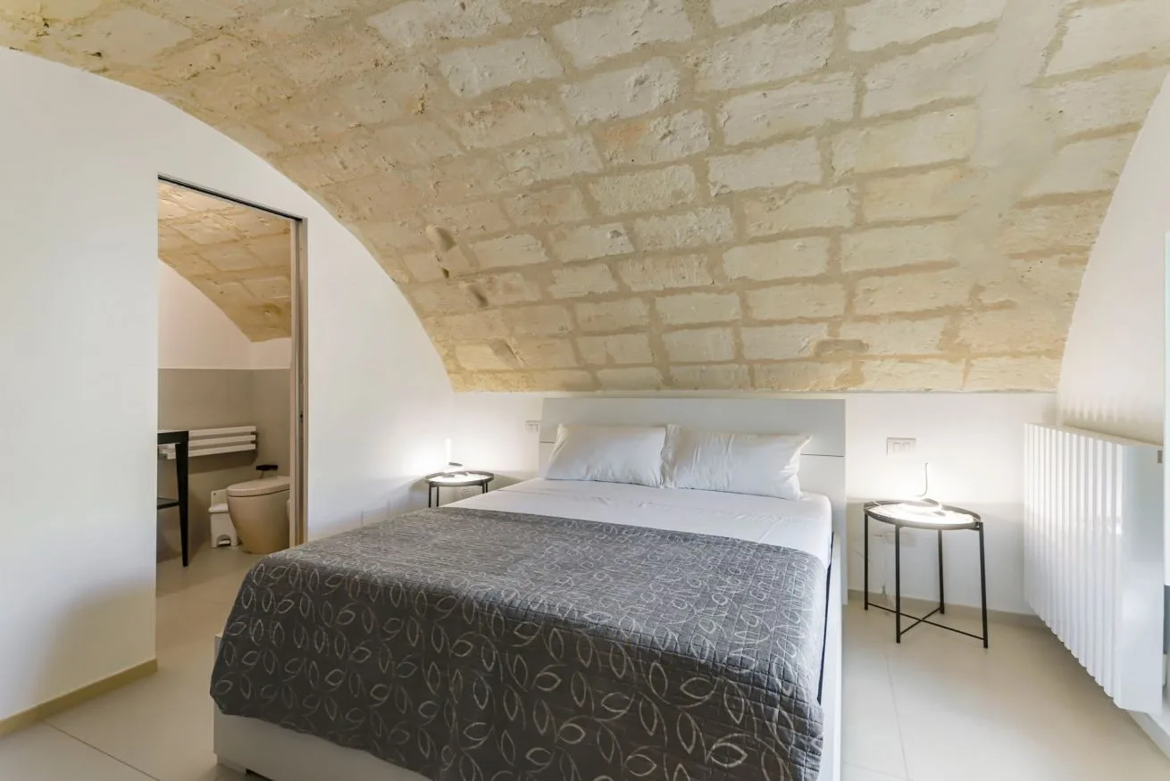 A bedroom with a bed beneath a low stone ceiling.