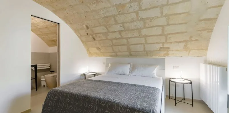 A bedroom with a bed beneath a low, exposed stone ceiling.