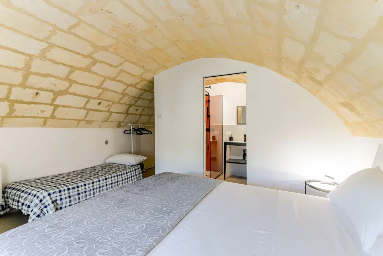 A bedroom with a bed beneath a curved stone ceiling.