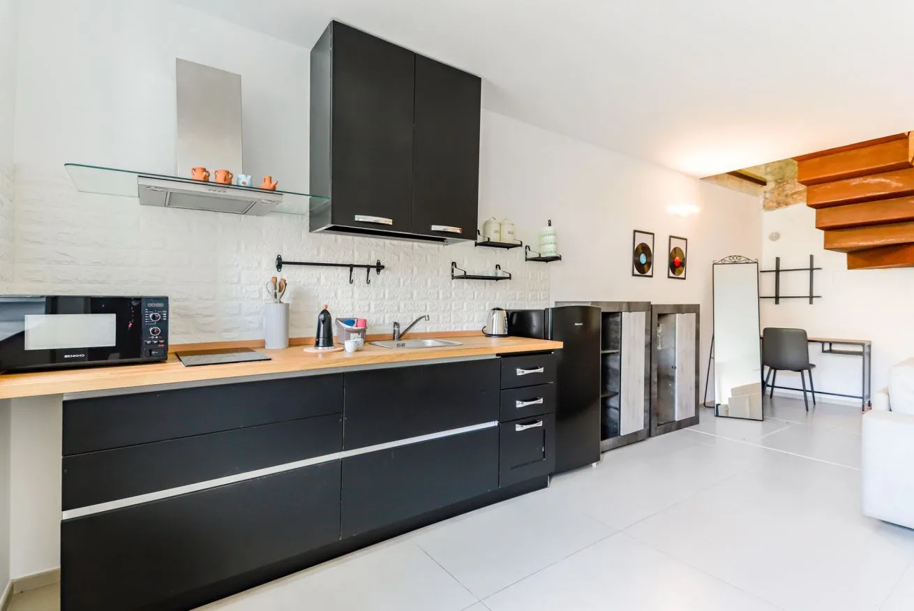 A modern kitchen with dark cabinets, a long counter, and a microwave.