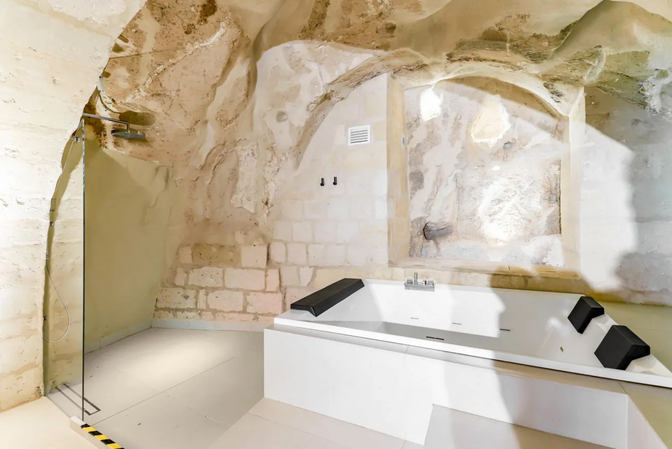 A bathroom with a built-in bathtub beneath a stone arch.