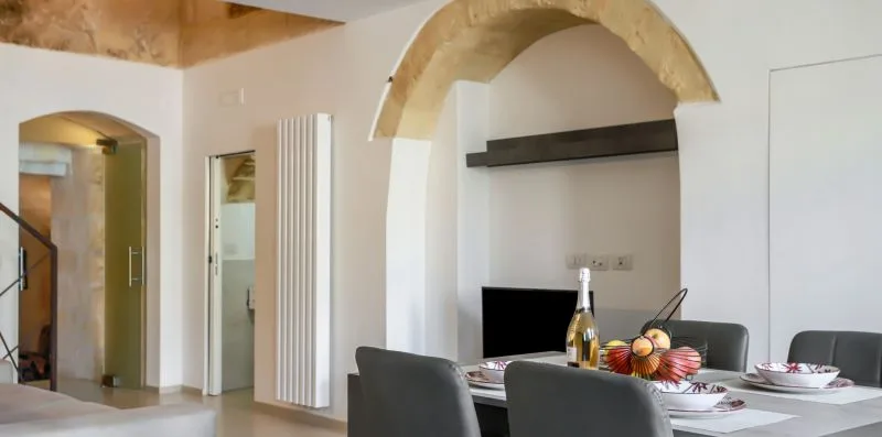 A dining area with a set table beneath a large arched wall feature.
