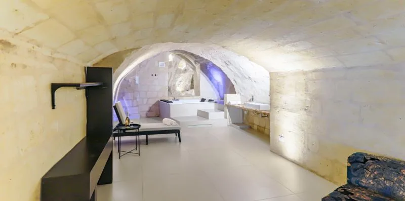 A stone room with an arched alcove, seating, and a bathtub.
