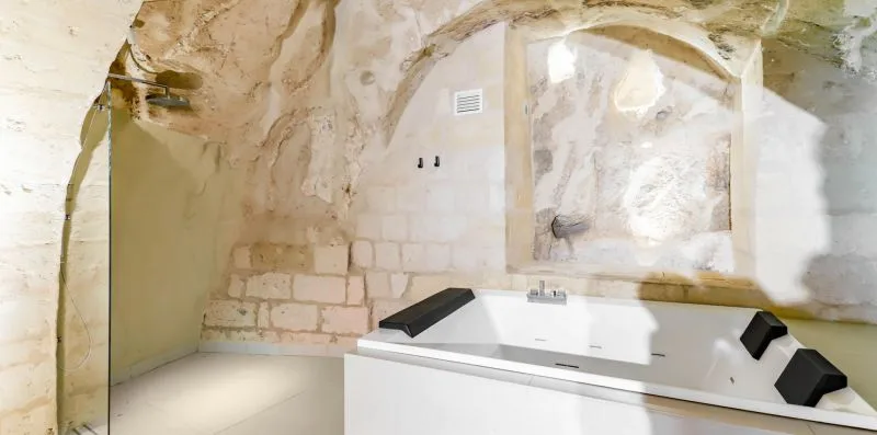 A bathroom with a built-in bathtub set beneath a stone arch.
