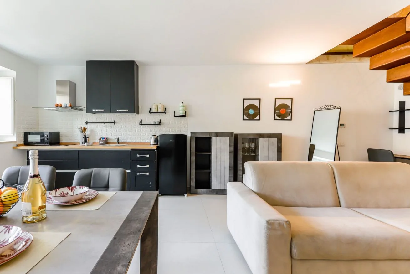 An open-plan living room and kitchen with dark cabinetry and a light-colored sofa.
