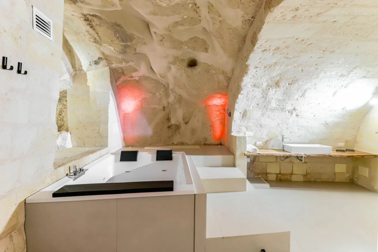 A stone bathroom with a large tub beneath vaulted ceilings.