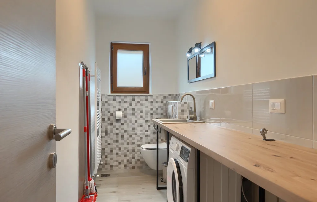 Un baño con una encimera larga, lavabo y lavadora.