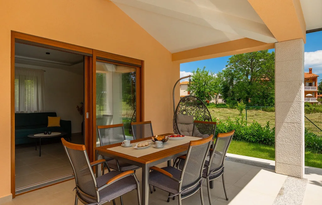 Un patio cubierto con una mesa de comedor y vistas al jardín.