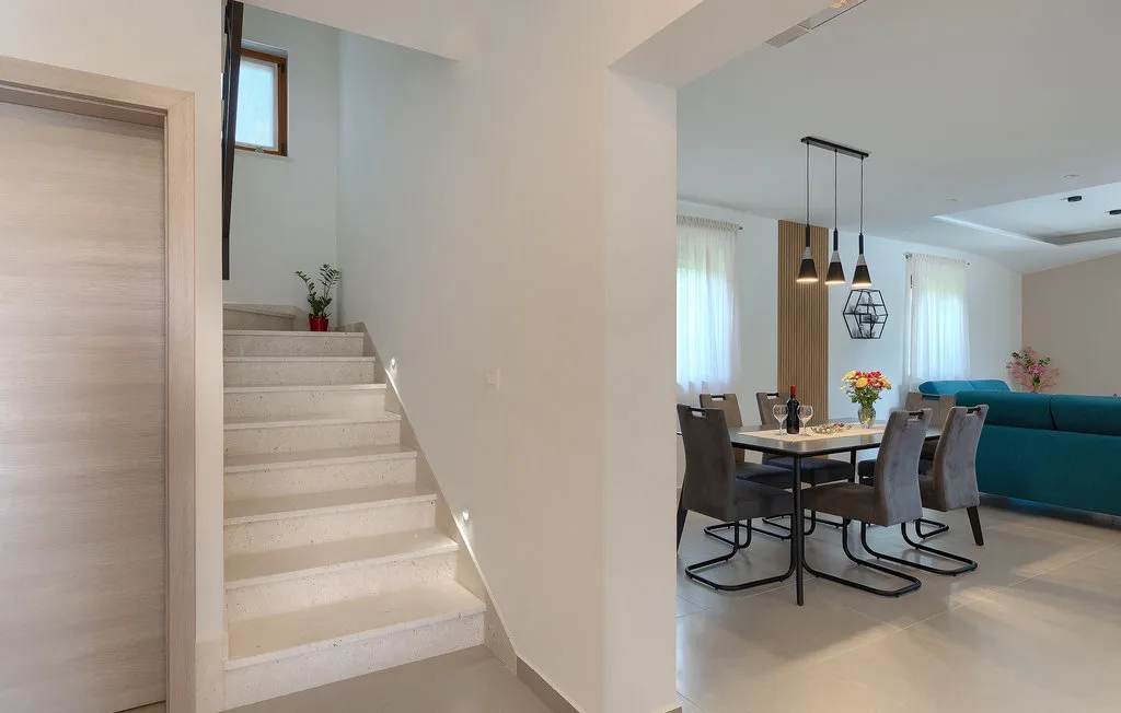 Un espacio abierto de comedor y sala con una mesa bajo lámparas colgantes.