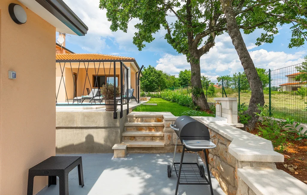 Un patio soleado con escalones, asientos y una barbacoa junto a la casa.
