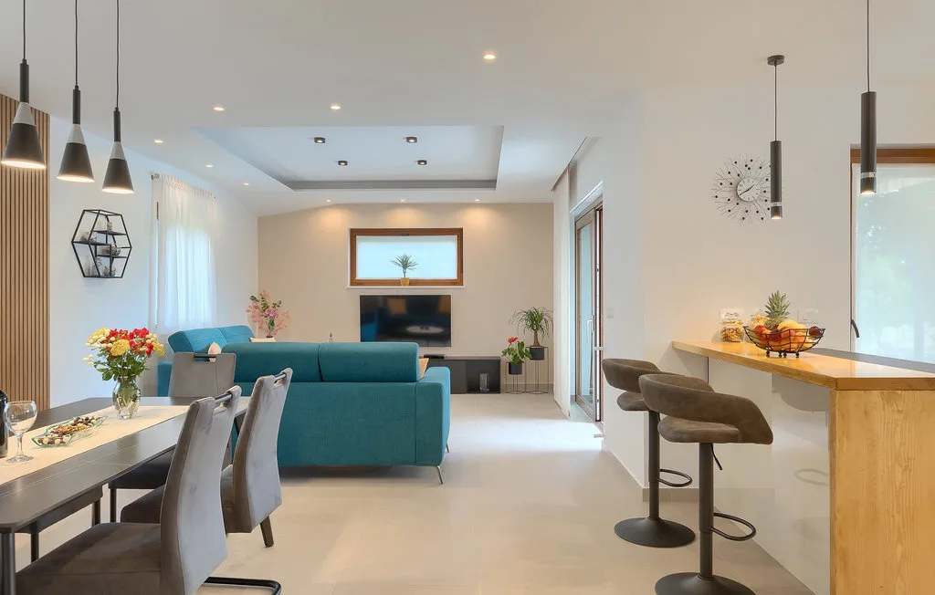 Una luminosa sala de estar y comedor de planta abierta con un sofá turquesa y una barra de cocina.