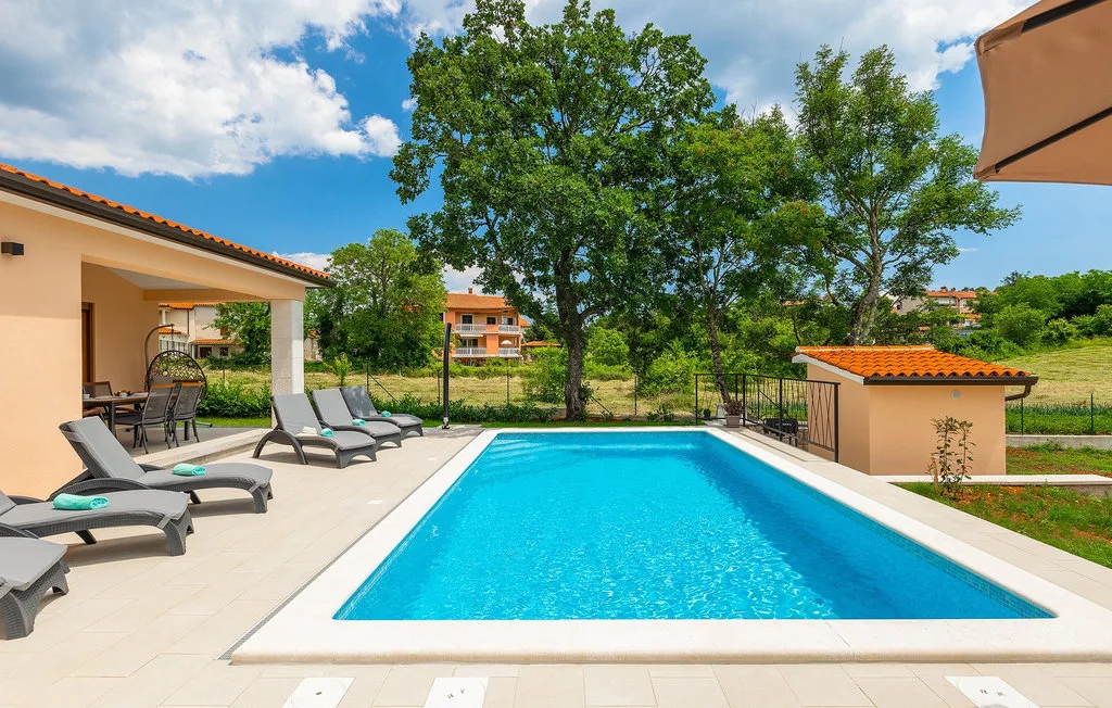 Una piscina al aire libre junto a un patio cubierto y asientos de descanso.