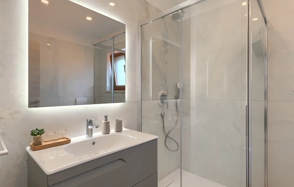Un baño luminoso con lavabo y ducha de vidrio.