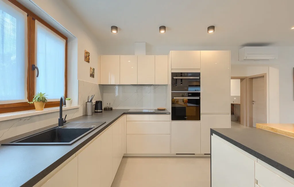 Una cocina moderna con gabinetes claros, encimeras oscuras y electrodomésticos integrados.
