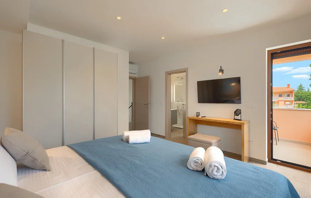 Un dormitorio con una cama, toallas dobladas y un televisor sobre un escritorio.